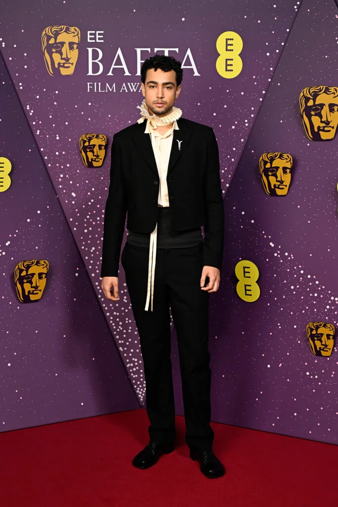 El actor Archie Madekwe posando en un conjunto negro en los premios BAFTA 2026