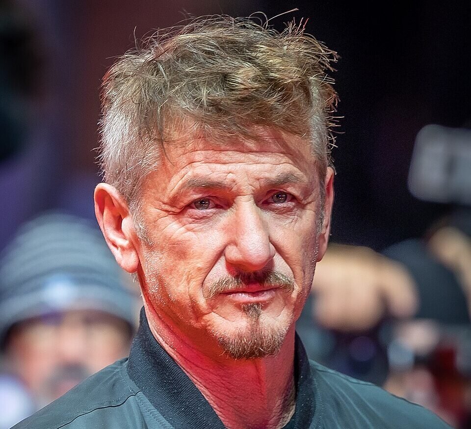Sean Penn mirando hacia la cámara con un rostro serio y una chaqueta color negra